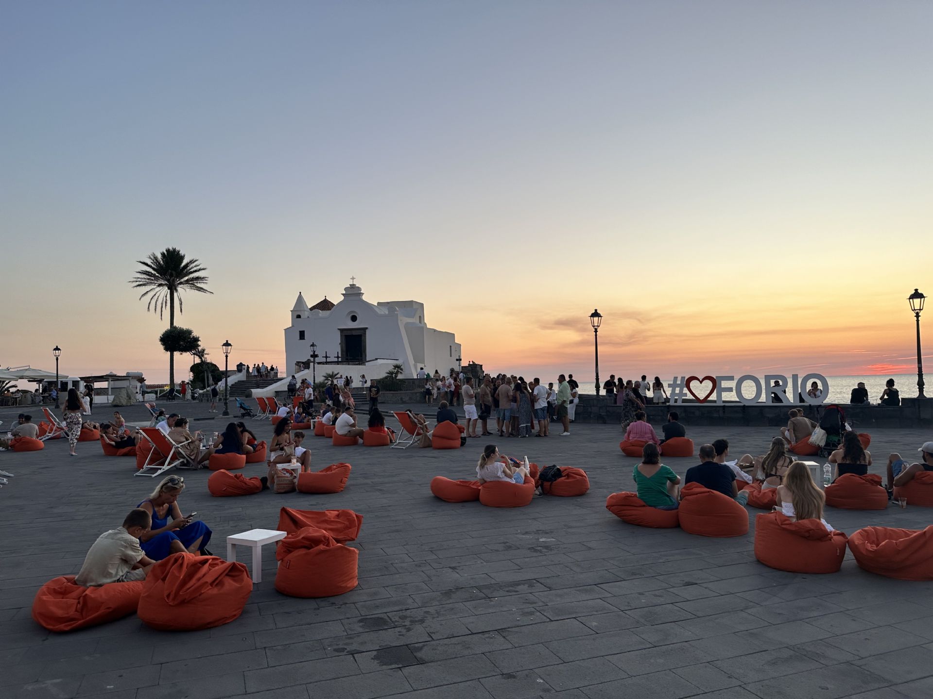 Una panoramica della piazza del Soccorso, il cuore pulsante dell'evento del tramonto. In questo suggestivo scenario, i partecipanti possono godersi il tramonto seduti comodamente su cuscini morbidi, sorseggiando un aperitivo e lasciandosi incantare dalla bellezza del paesaggio che si tinge dei colori caldi del tramonto