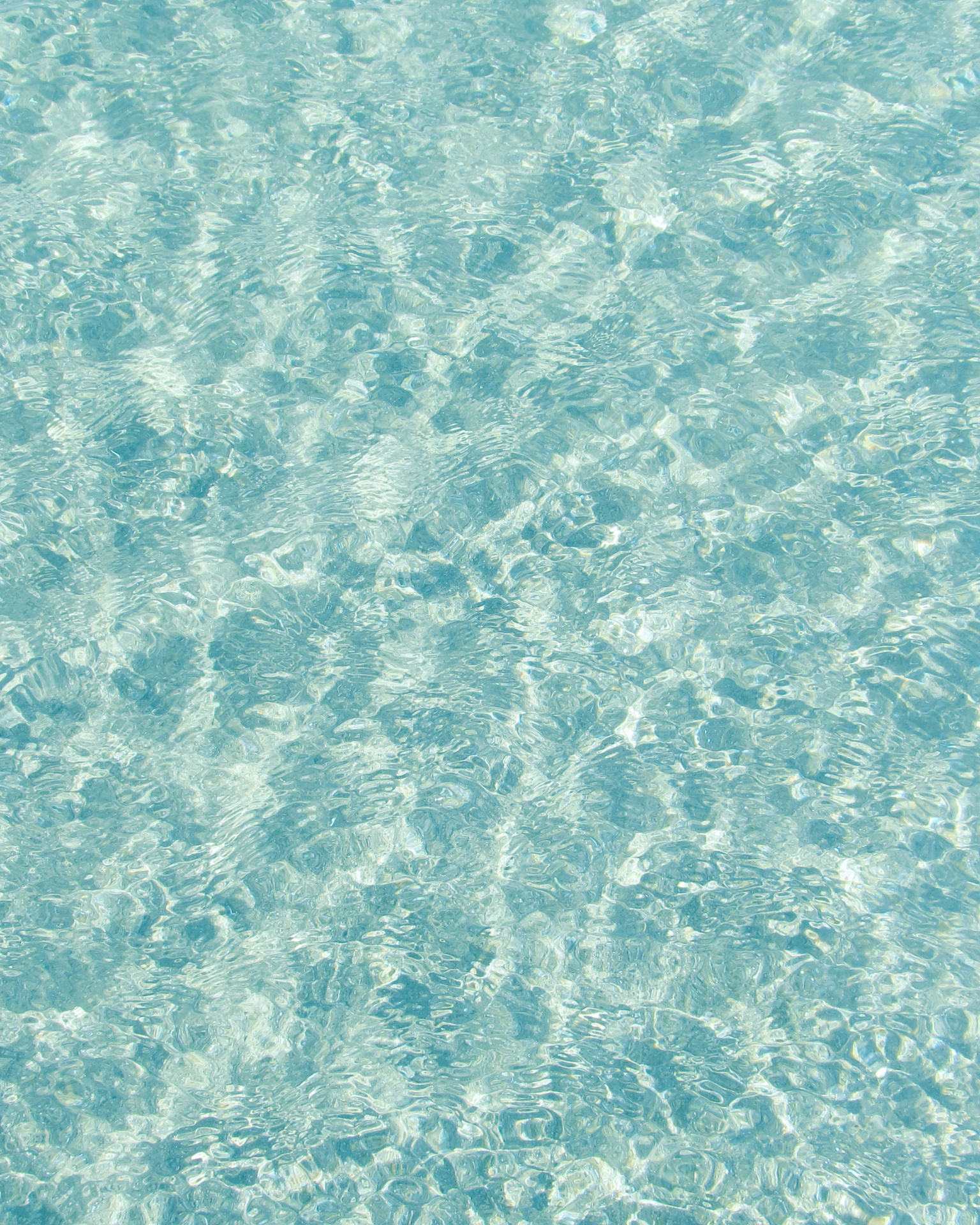 Acqua trasparente e azzurra, calma e profonda, con leggere onde che si muovono lentamente sotto il cielo sereno.