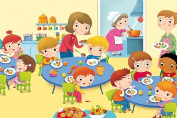 Bambini seduti a tavola mentre consumano il pasto, affiancati dal personale addetto alla mensa.